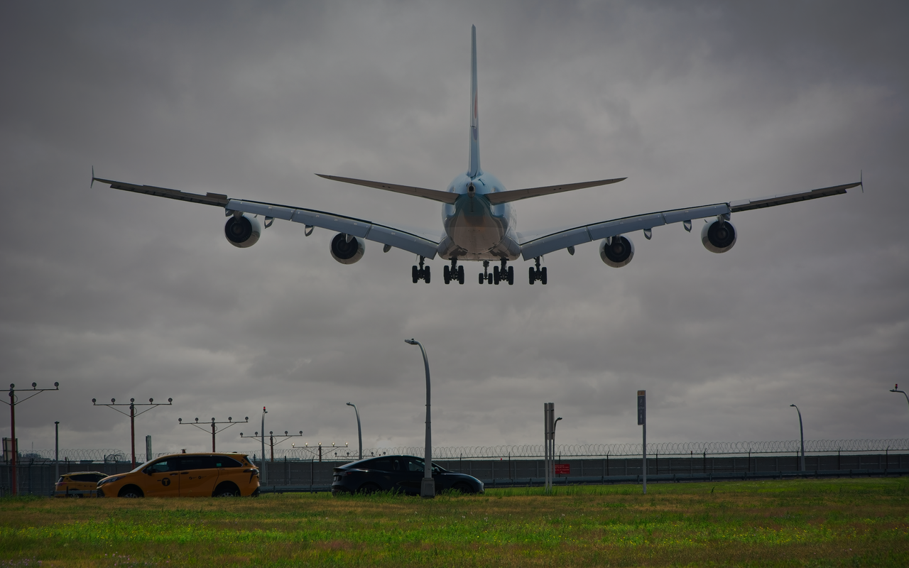 Services A passenger airplane lands at New York airport with cloudy skies, showcasing aviation and urban transport.
