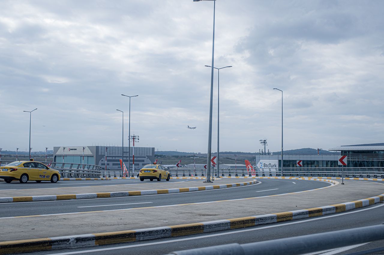 Mastering the First Impression: Your intriguing post title goes here A busy airport scene showing taxi cabs, runway, and an airplane taking off under a cloudy sky.