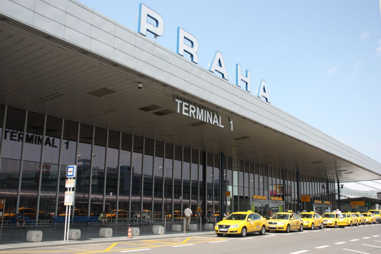 Crafting Captivating Headlines: Your awesome post title goes here Exterior view of Praha Airport's Terminal 1 with a line of yellow taxis awaiting passengers.